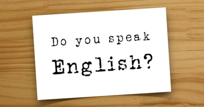 a piece of paper with the words "do you speak english" written on it, laying on a wooden surface